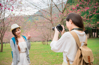 朋友服用有乐趣的生活方式享受寻找在樱花公园户外活动樱花的照片。亚洲女子在日本和韩国春假期间拍摄的照片与照片的相机。