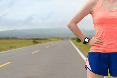 专业运动员穿的运动心脏率的SmartWatch的健身锻炼，并通过技术的产品在公路背景测试创个人最好成绩肖像。