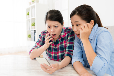 漂亮美丽的姐妹们使用移动手机一起在线浏览网站信息，寻找坏消息感到震惊。