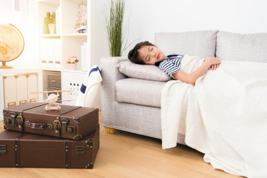 诱人的可爱的小女孩玩游戏的行程很长一段时间感到有些疲倦，在游戏室躺在沙发上睡觉休息。