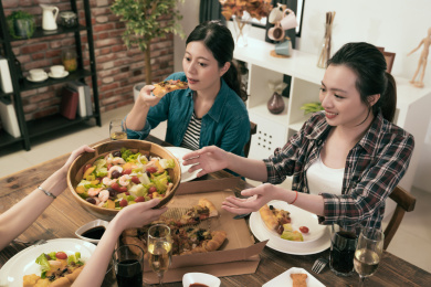 吃晚饭的朋友一起在家里的饭厅传递沙拉给对方。