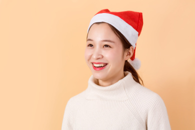 开心的美丽亚洲年轻女性戴着圣诞帽，室内棚拍