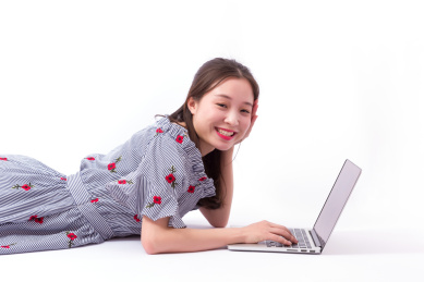 年轻女人趴着使用笔记本电脑上