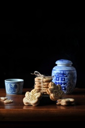 桌子上的一个青花喜字瓷罐前的一摞枫叶形饼干和一个青花茶杯