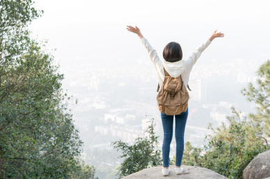 一个人站在山顶的石头上看城市