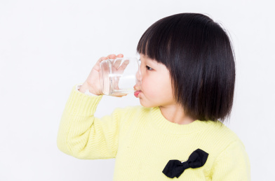 拿玻璃水杯喝水的小女孩