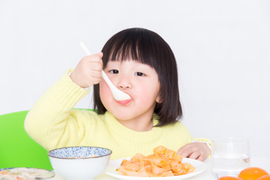 饭桌上自己乖乖吃饭的小女孩