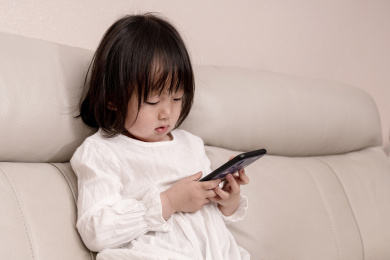 一个中国小女孩坐在沙发上玩手机