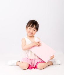 手拿白板穿裙子的小女孩坐在地上