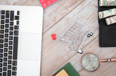 俯视桌子上的笔记本电脑和购物车模型及其它相关物品