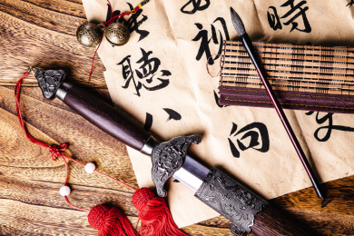 中国风正上方视角特写摆在木桌上的毛笔书法中国剑和毛笔