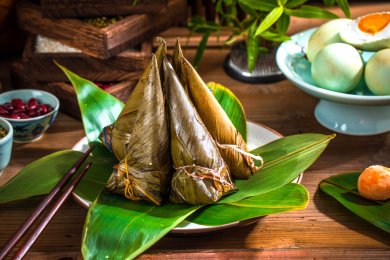 五个立着放着复古盘里的尖角粽子，旁边摆放着粽子食材