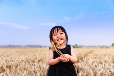 麦田里拿着麦穗开心玩耍的小女孩
