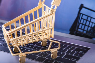 特写笔记本电脑键盘上放着一台金色的购物车