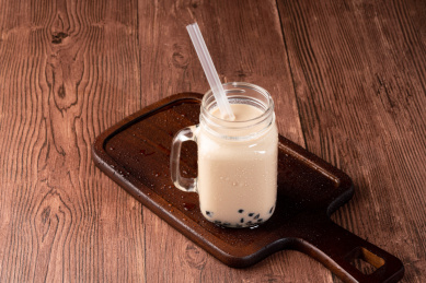 红褐色木板桌面上玻璃杯里的珍珠奶茶