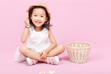 坐在地上手拿贝壳开心玩耍的小女孩