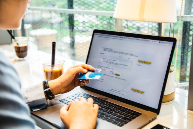 咖啡馆里女性手持信用卡在笔记本电脑键盘上输入信息