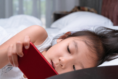 躺在床上看手机的中国女孩