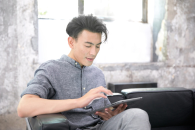 坐在沙发上玩平板电脑的年轻男人