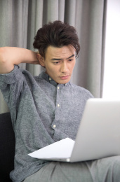 坐在沙发上使用电脑工作的商务男性