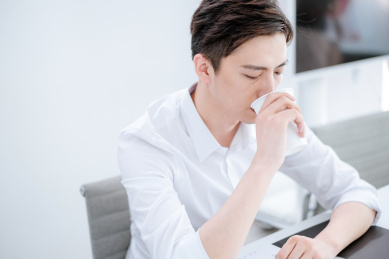 坐在办公桌前喝水的中国男性