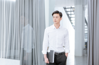 拿文件夹站在办公室的年轻中国男性