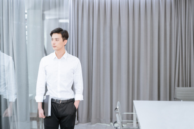 拿文件夹站在办公室的年轻中国男性