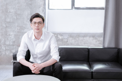 穿白色衬衣坐在黑色皮质沙发上的年轻男士