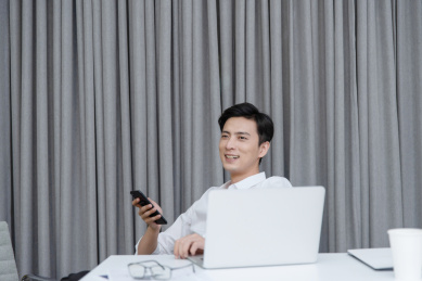 在办公桌前放松地使用手机的年轻男性白领