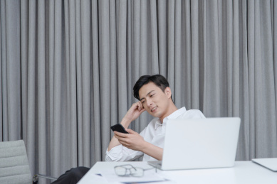 在办公桌前放松地使用手机的年轻男性白领