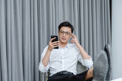 在办公桌前放松地使用手机的年轻男性白领