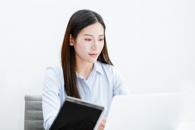 着职业装使用笔记本电脑的年轻女性