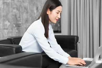 坐在沙发上使用笔记本办公的亚裔女人