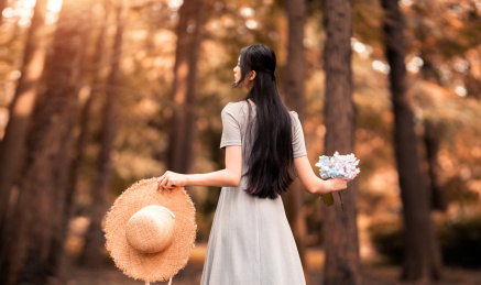 身穿蓝色的长裙的女生手拿鲜花的背影特写
