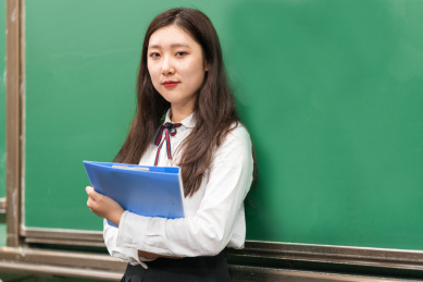 校园教室内黑板前,拿着文件夹的女人