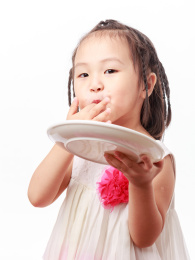 端着空盘子吃手指的小女孩