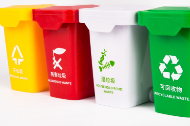 白色背景上放着一排彩色垃圾桶，用玩具组合来表达垃圾分类的概念