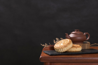 深色背景前摆放在红木桌面上的月饼