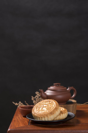 深色背景前摆放在红木桌面上的月饼