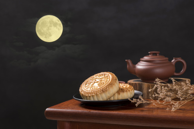 深色背景前摆放在红木桌面上的月饼