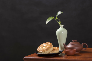 深色背景前摆放在红木桌面上的月饼