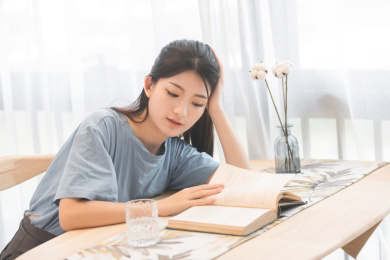  在家里，坐在椅子上正在看书的美丽女孩