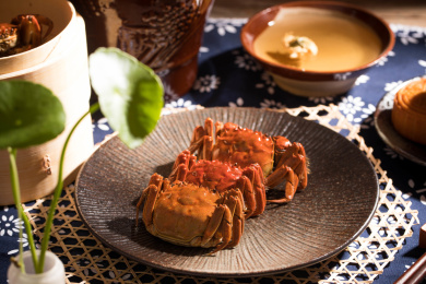 一个盘子里装着三个清蒸好的大闸蟹，旁边还放着月饼和蒸笼