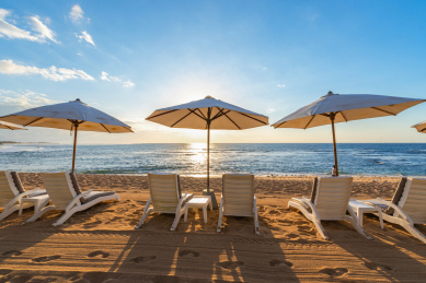 蓝天白云下海边的遮阳伞和沙滩椅