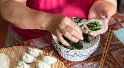 中国传统美食慈祥的外婆正在包着饺子和饺子馅