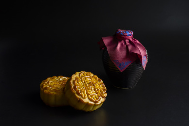 黑色背景中放着的月饼和酒壶