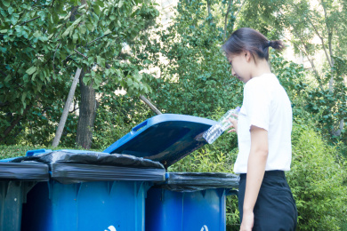 一位年轻的亚裔女孩背对镜头做垃圾分类