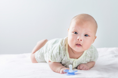  白色背景前趴着的初生婴儿和安抚奶嘴