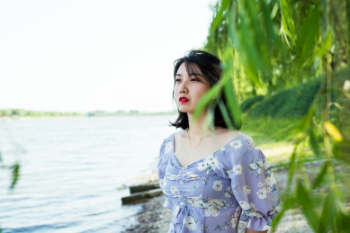 在河边站着的女孩望着远处，夏天户外风景和美女