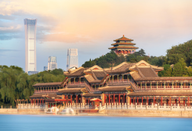 中国北京北海公园蓝色湖面对岸的长廊及远景景山上的万春亭和CBD现代建筑